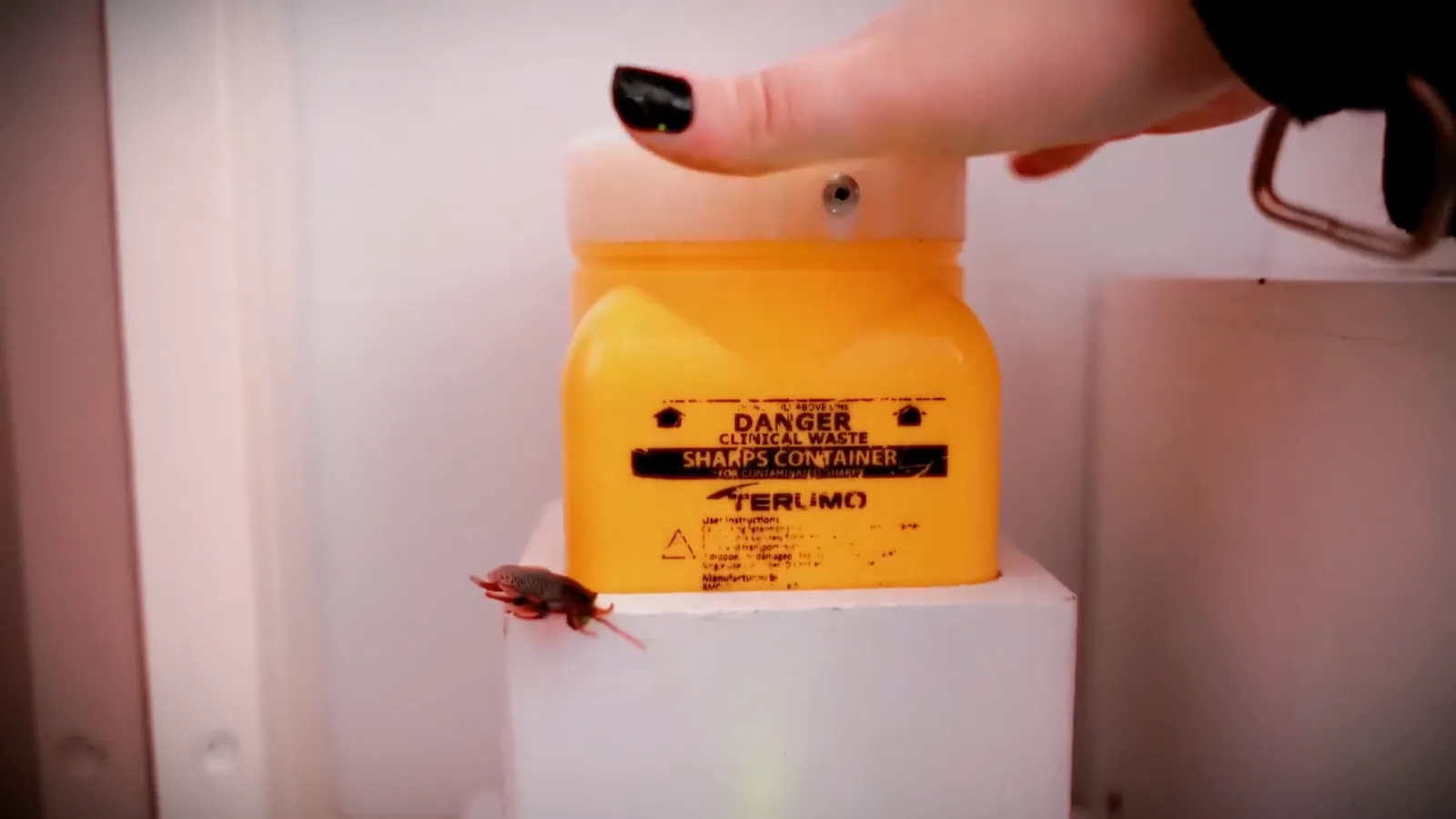 A yellow sharps container on a white shelf in the Asylum escape room