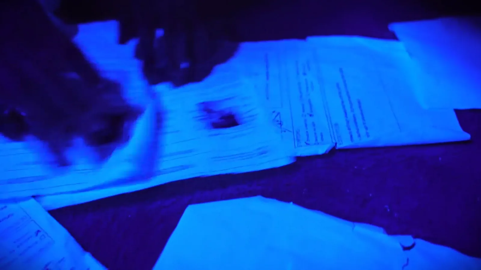 Patient files spread under ultraviolet light in Asylum